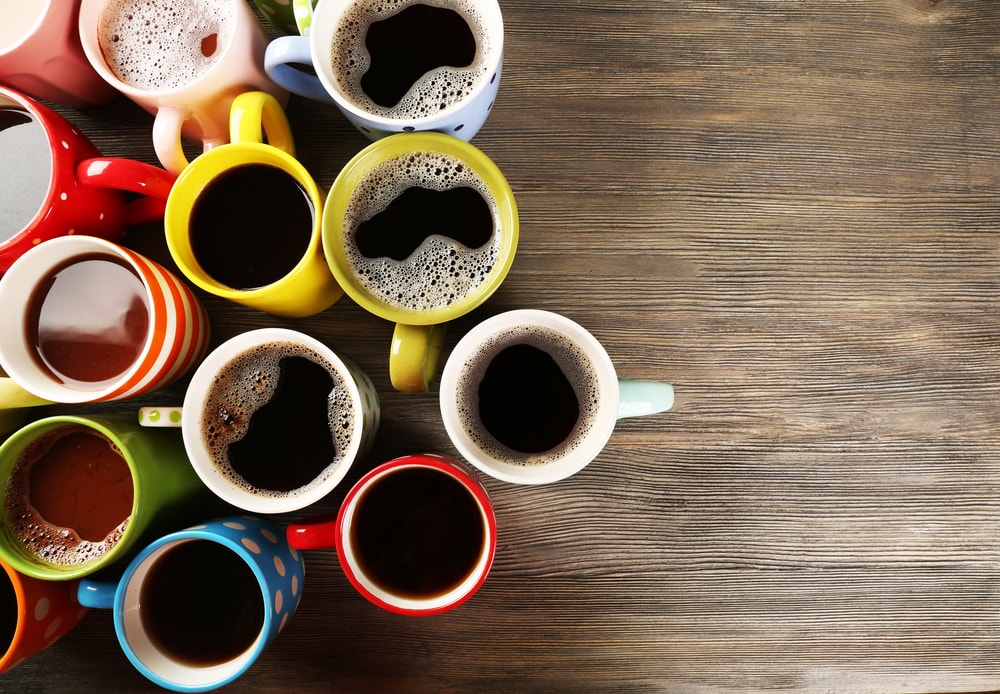 Many cups of coffee on wooden background