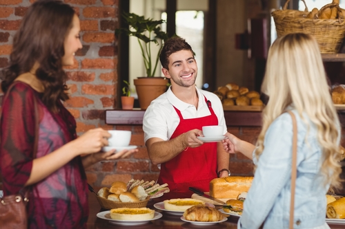 Waiter serving a coffee to a customer at the coffee shop